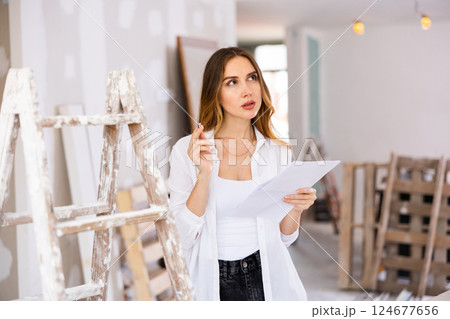 Long-haired girl taking notes while planning house renovation 124677656