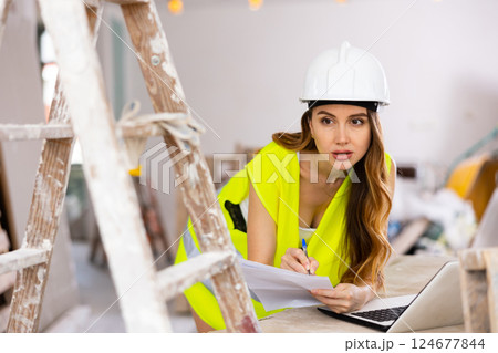 Sexy woman in a vest makes checks repair plan on the laptop 124677844