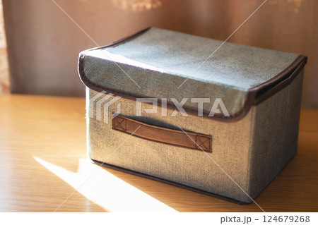 A shiny silver box featuring a brown handle sits atop a wooden table 124679268