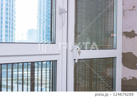 A detailed close up shot of a window featuring a key inserted in it 124679289