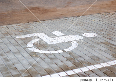 A handicap accessibility sign is painted on a brick pavement surface 124679314
