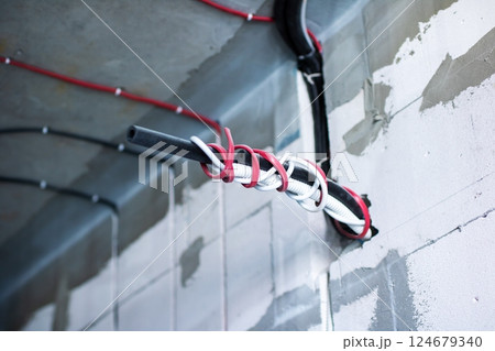 A bunch of wires and cables are all connected to a wall socket 124679340