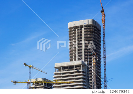A construction site with cranes and a blue sky backdrop 124679342
