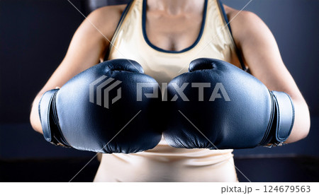 woman in boxing gloves, a person holding up a pair of black boxing gloves, suggesting themes of fitness, strength, determination, and combat sports 124679563