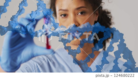 Image of blue dna strand over biracial female doctor holding blood sample 124680222