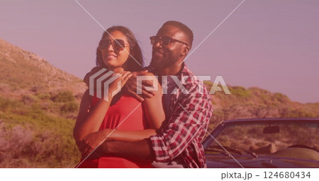 Image of light shade over biracial couple embracing on car at seaside 124680434