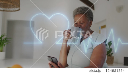 Image of cardiograph with heart over senior biracial woman using smartphone at home 124681234