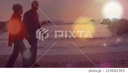 Walking on beach, couple with light bokeh image over ocean waves Walking on beach, couple with light bokeh image over ocean waves 124682365