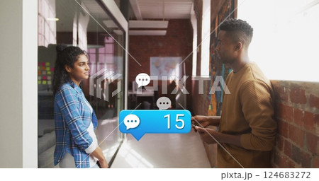 Image of media icons over diverse colleagues discussing work in office 124683272