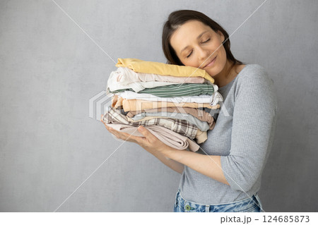 Laundry, woman holds stack of clothes in her hands after dry cleaning. housework, cleaning ironing. Laundry, woman holds stack of clothes in her hands after dry cleaning. housework, cleaning ironing. 124685873