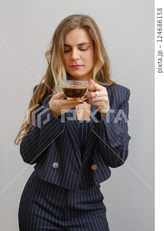 Woman in a striped suit enjoying coffee in a minimalist setting at a modern hour Woman in a striped suit enjoying coffee in a minimalist setting at a modern hour 124686158