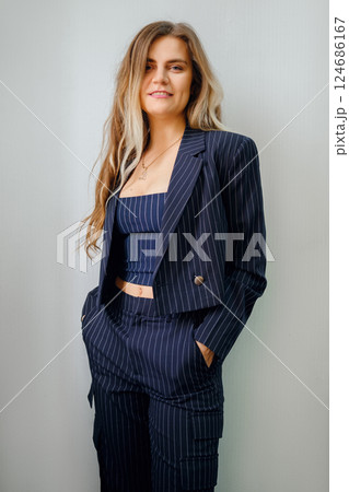 Stylish woman in pinstripe suit posing confidently against a neutral background 124686167