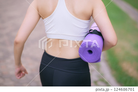 back of fitness yoga woman walking in the park with yoga mat 124686701
