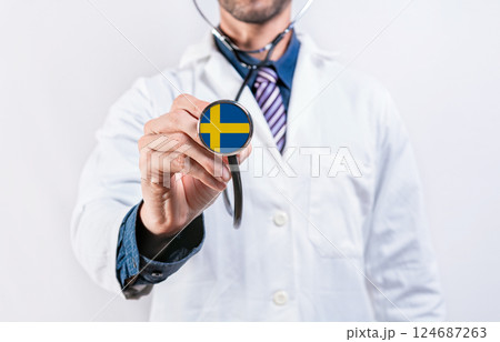 Sweden healthcare system, doctor holding stethoscope. Sweden health and medical insurance concept Sweden healthcare system, doctor holding stethoscope. Sweden health and medical insurance concept 124687263