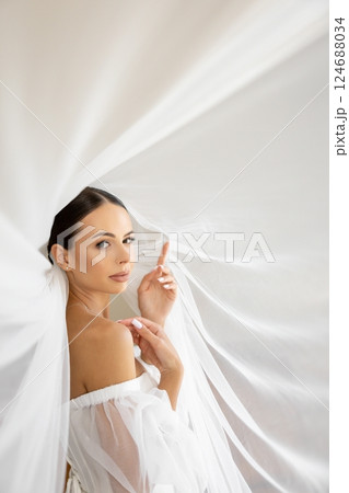 Bride holding veil looking away in wedding dress Bride holding veil looking away in wedding dress 124688034