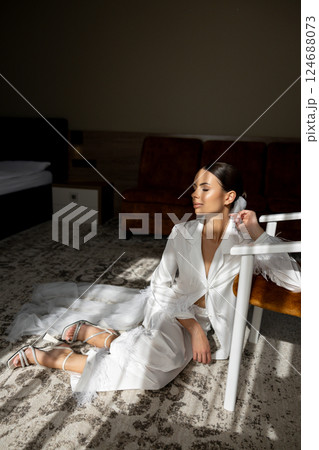 Bride wearing white suit sitting on carpet in hotel room Bride wearing white suit sitting on carpet in hotel room 124688073