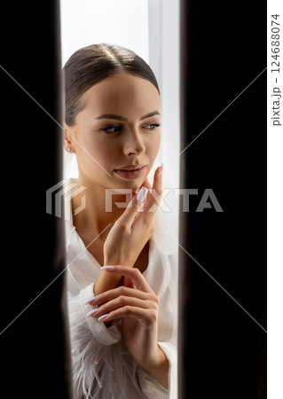 Bride hiding behind curtains looking down with closed eyes and hands near her face Bride hiding behind curtains looking down with closed eyes and hands near her face 124688074