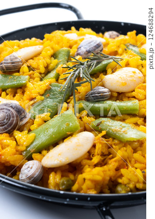 Traditional Valencian paella with rabbit, chicken, garrofon beans, snails, Moroccan green beans and saffron on black background. 124688294