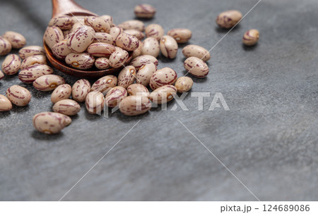 Wooden spoon full of dried pinto beans on gray closeup. Traditional Latin American legumes Wooden spoon full of dried pinto beans on gray closeup. Traditional Latin American legumes 124689086