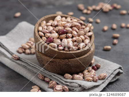 Wooden bowl full of dried pinto beans on napkin on gray closeup. Traditional Latin American legumes Wooden bowl full of dried pinto beans on napkin on gray closeup. Traditional Latin American legumes 124689087