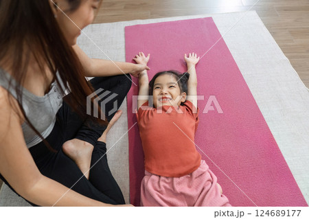 Fun Stretching and Laughter. A playful mother and daughter stretching together on a yoga mat. 124689177