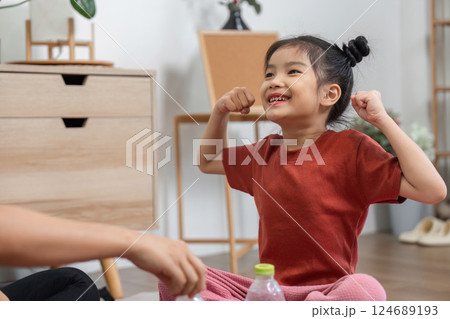 Strength and Joyful Play. A little girl showcasing her muscle with pride during a playful exercise routine. 124689193