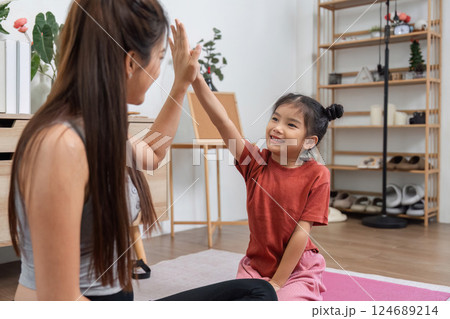 Fitness and Encouragement. A mother and daughter sharing a joyful moment during a home workout, motivating each other. 124689214