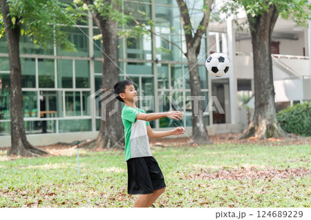 Soccer Skills and Focus. A boy practices his soccer skills by catching a ball in the park. 124689229
