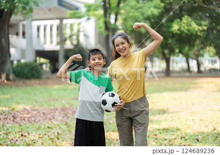 Fitness and Family Bonding. A cheerful boy and a woman show their strength while enjoying outdoor soccer activities together. Fitness and Family Bonding. A cheerful boy and a woman show their strength while enjoying outdoor soccer activities together. 124689236