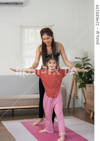 Strength and Connection. A mother guides her daughter through an encouraging exercise session. Strength and Connection. A mother guides her daughter through an encouraging exercise session. 124689239