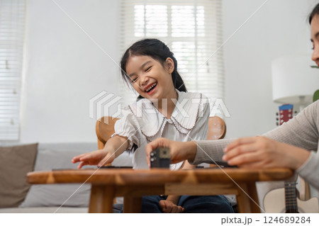 Playful Moments and Family Connection. A young girl enjoys a playful moment with her mother during their game. 124689284