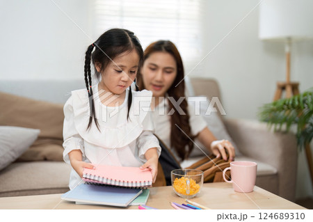 Studying and Exploring Creativity. A child organizes her school supplies, assisted by her mother as they prepare for the school year. Studying and Exploring Creativity. A child organizes her school supplies, assisted by her mother as they prepare for the school year. 124689310
