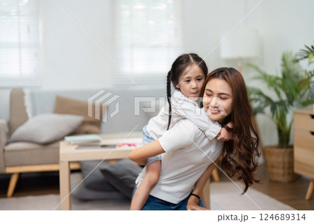 Back to School and Affectionate Moments. A mother carries her daughter on her back in a loving embrace. Back to School and Affectionate Moments. A mother carries her daughter on her back in a loving embrace. 124689314
