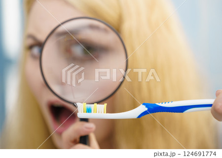 Woman looking at toothbrush through loupe 124691774