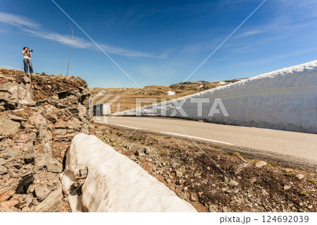 Tourist taking photo from high snow wall at road, Norway 124692039