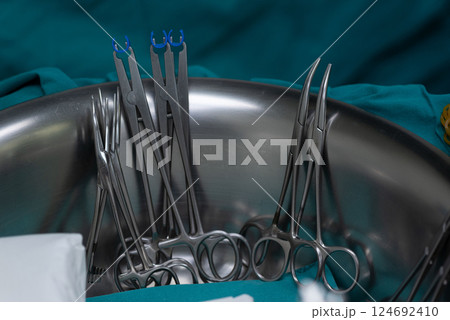 Surgical clamps and forceps in stainless steel bowl on medical drape, prepared for medical procedure Surgical clamps and forceps in stainless steel bowl on medical drape, prepared for medical procedure 124692410