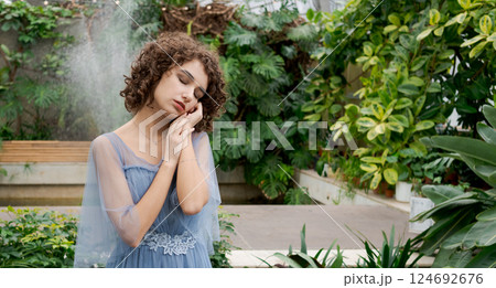 Woman in a blue dress is standing in a garden 124692676