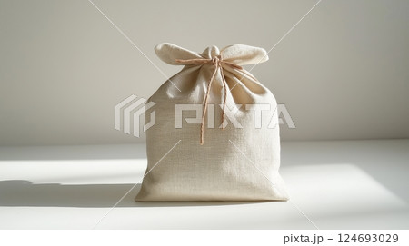 Soft linen bag tied with string placed on a clean surface in daylight 124693029