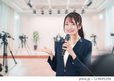 記者会見場からレポートをする女性のアナウンサー 124695206