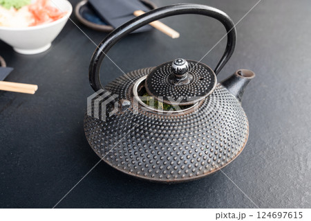 Japanese tea pot, black metal teapot, traditional iron kettle for tea drinking while waiting for sushi Japanese tea pot, black metal teapot, traditional iron kettle for tea drinking while waiting for sushi 124697615