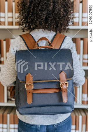 Back view of a female student with backpack in a library. A thoughtful female student gazes at the bookshelves, her backpack hinting at her dedication to education. 124697996