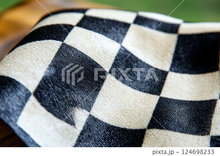 Checkered fabric laid flat on wooden surface in natural light creates a striking visual contrast and texture 124698233
