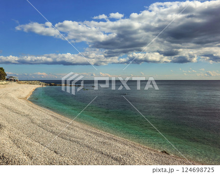 Pebble beach and blue sea with white clouds. Pebble beach and blue sea with white clouds. 124698725