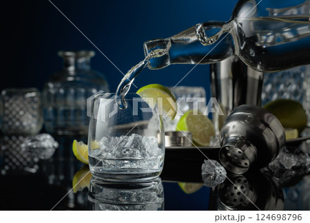 Vodka is poured into a glass with ice. 124698796