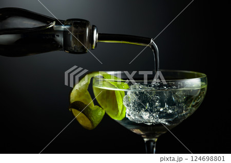 Vodka or gin is poured into a glass with ice. Vodka or gin is poured into a glass with ice. 124698801