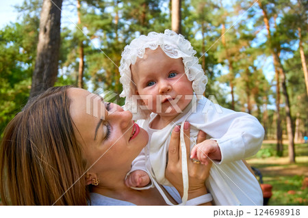 Young happy mother with a cute breast newborn baby in a sunny forest Young happy mother with a cute breast newborn baby in a sunny forest 124698918