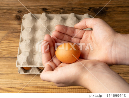 Hand Holding Raw Chicken Eggs Above Wooden Table Background, Taking Brown Eco Bio Egg 124699448