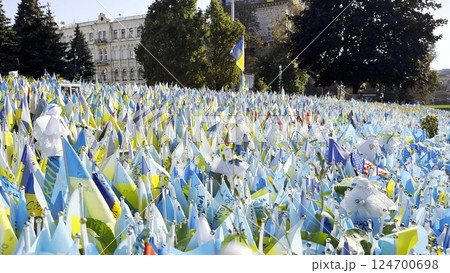 Many small blue-yellow flags with names of the dead war against russia. Memorial of the fallen soldiers, children, women in the capital of Ukraine. Concept of tragedy and misfortune. Close up Many small blue-yellow flags with names of the dead war against russia. Memorial of the fallen soldiers, children, women in the capital of Ukraine. Concept of tragedy and misfortune. Close up 124700698