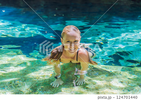 Female tourist enjoying a refreshing swim in a Mexican cenote with turquoise water. Adventure, travel, and nature exploration concept 124701440