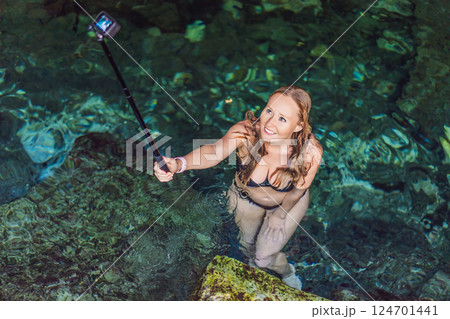 Female tourist enjoying a refreshing swim in a Mexican cenote with turquoise water. Adventure, travel, and nature exploration concept Female tourist enjoying a refreshing swim in a Mexican cenote with turquoise water. Adventure, travel, and nature exploration concept 124701441